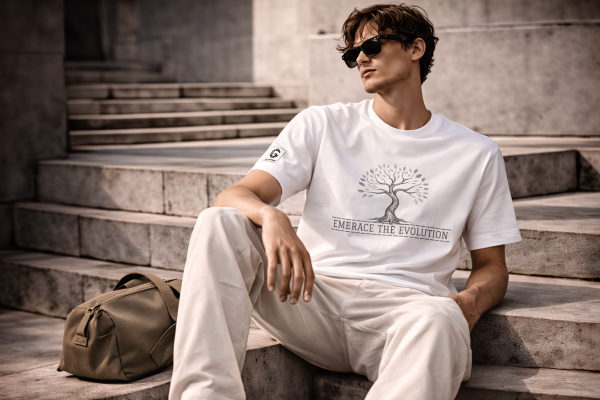 Man sitting on steps wearing a white t-shirt with a tree design and text, next to a green bag.